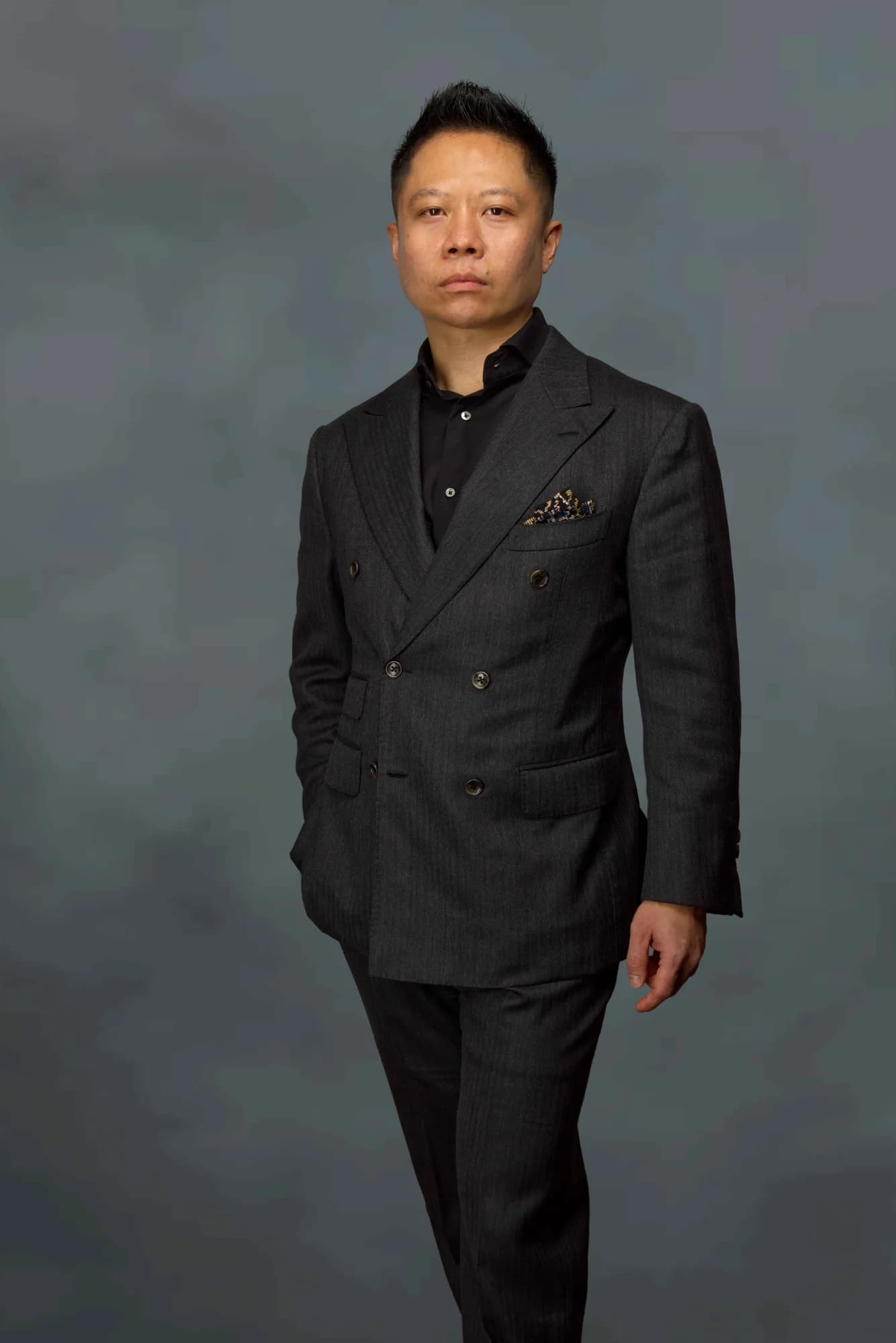 Corporate portrait of a man in a black suit on a dark grey backdrop