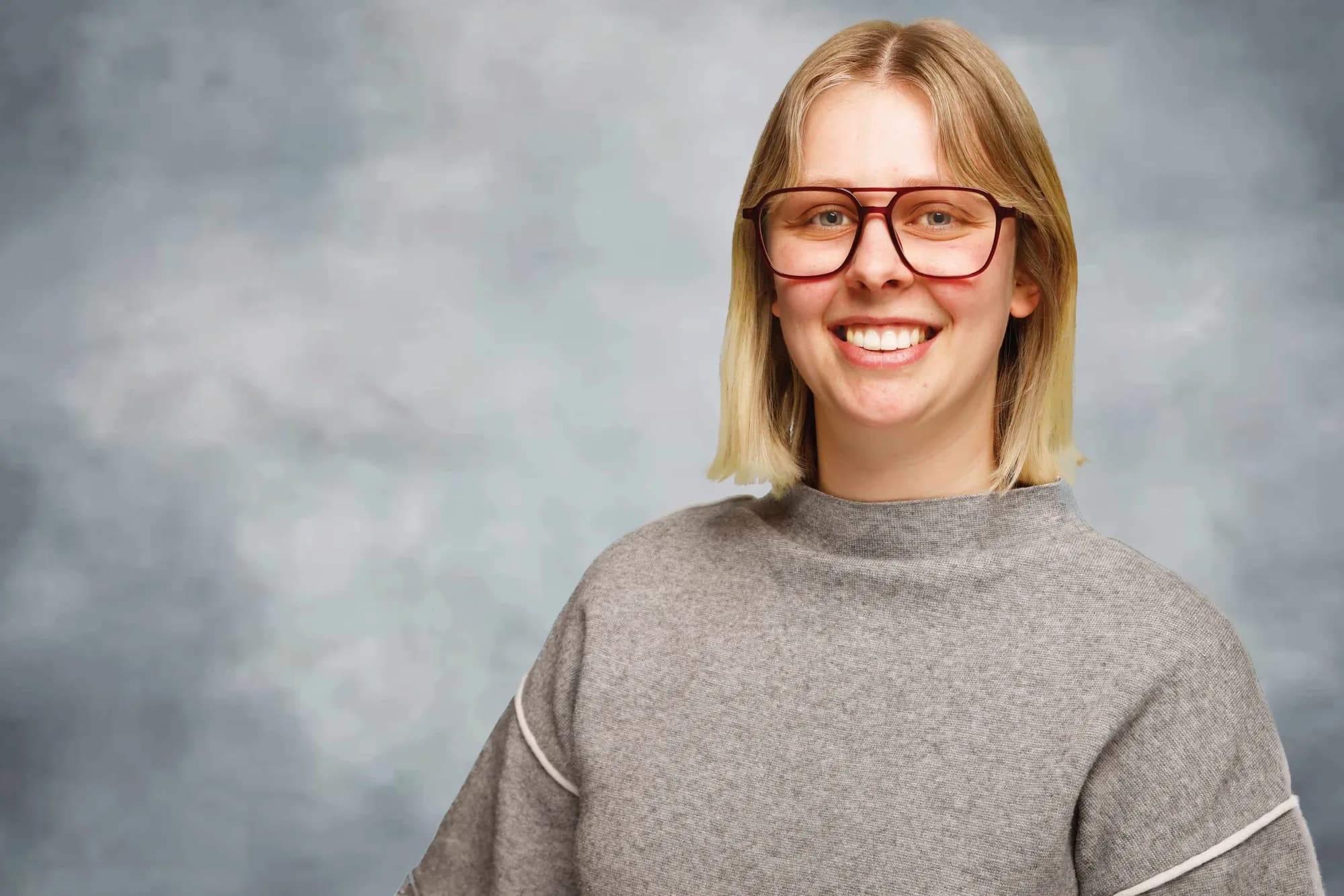 Corporate portrait of a woman in a grey sweater on a soft grey backdrop, Sydney